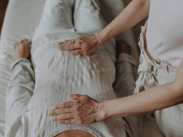Kristallklangschale im Einsatz bei einer Meditation mit einer Frau die unter der Klangschale liegt und so den Sound empfängt